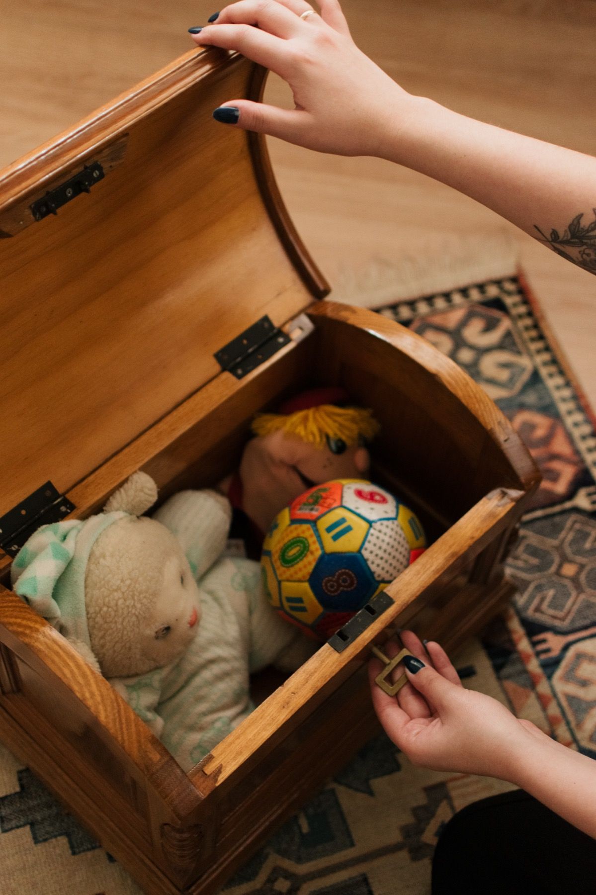 Baú de brinquedos aberto, com bichos de pelúcia e uma bola colorida